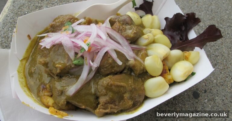 Bowl of Peruvian seco de cordero lamb stew with green cilantro sauce, rice and potatoes